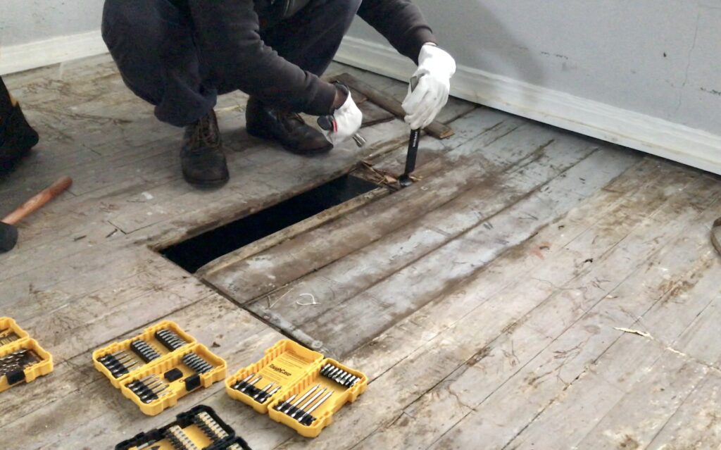 man removing original hardwood floors with tools all around him