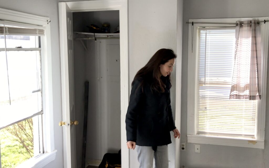 woman next to tiny closet in small fixer upper house 