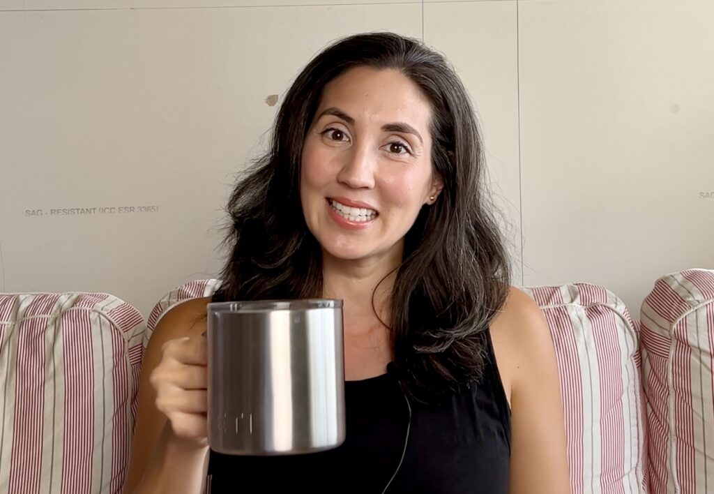 woman smiling and holding up a cup of coffee