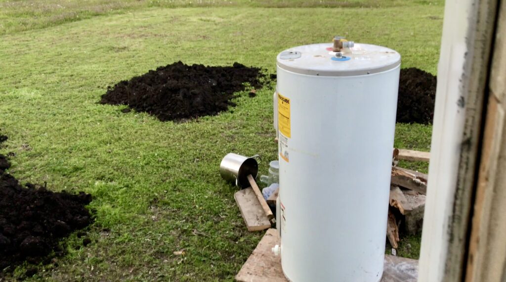 excavation dirt in backyard with water heater