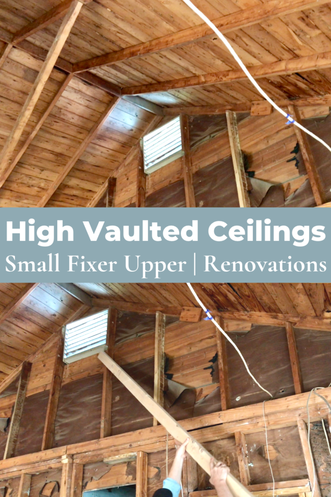 vaulted ceiling frames exposed in small fixer upper and man holding up wood frame under vent at the peak of small fixer upper with vaulted ceiling exposed