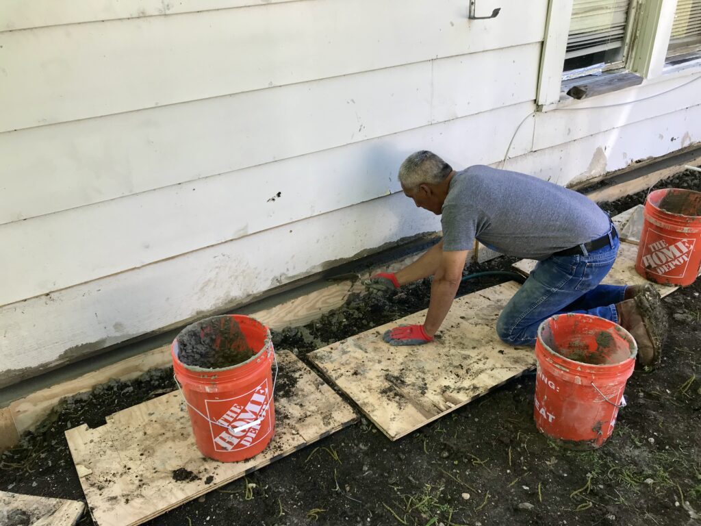 man leveling out concrete on foundation footer