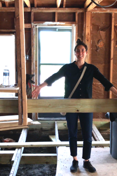 woman looking around fixer upper at framing work