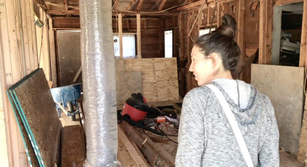 woman in small fixer upper house with framing exposed