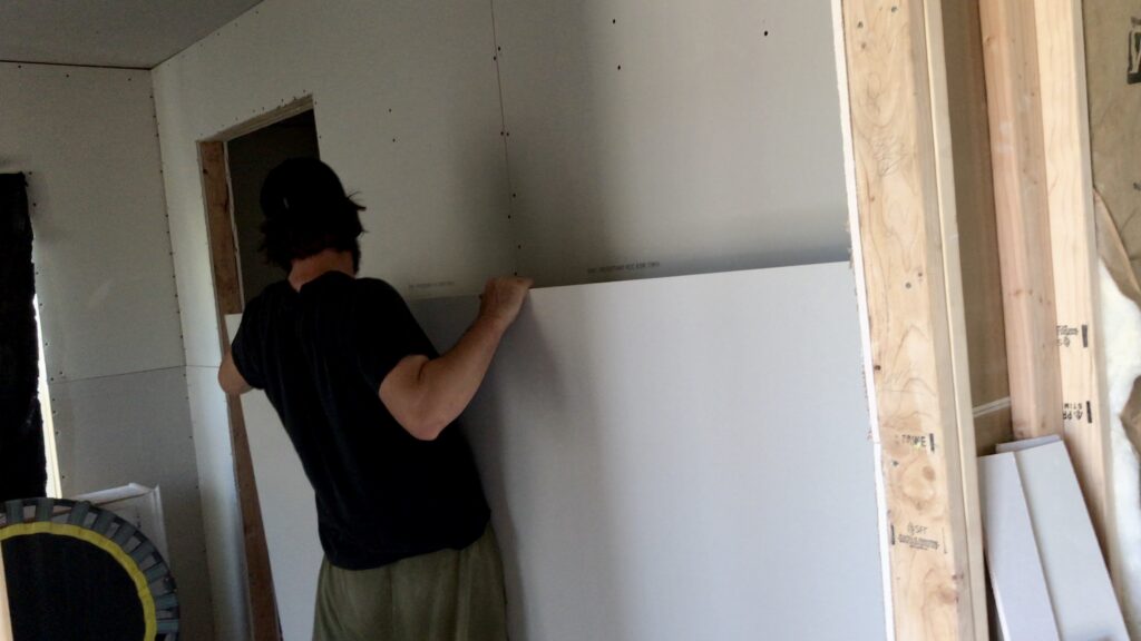 man stacking drywall in room