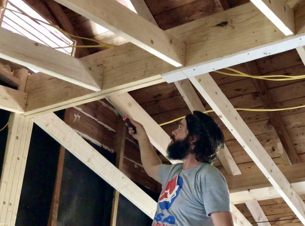 man pointing to flat vaulted ceiling beam
