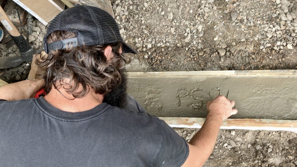 man writing in wet cement