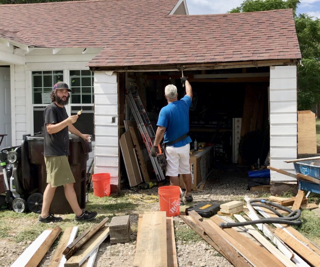 two men working on garage framing and new door installation
