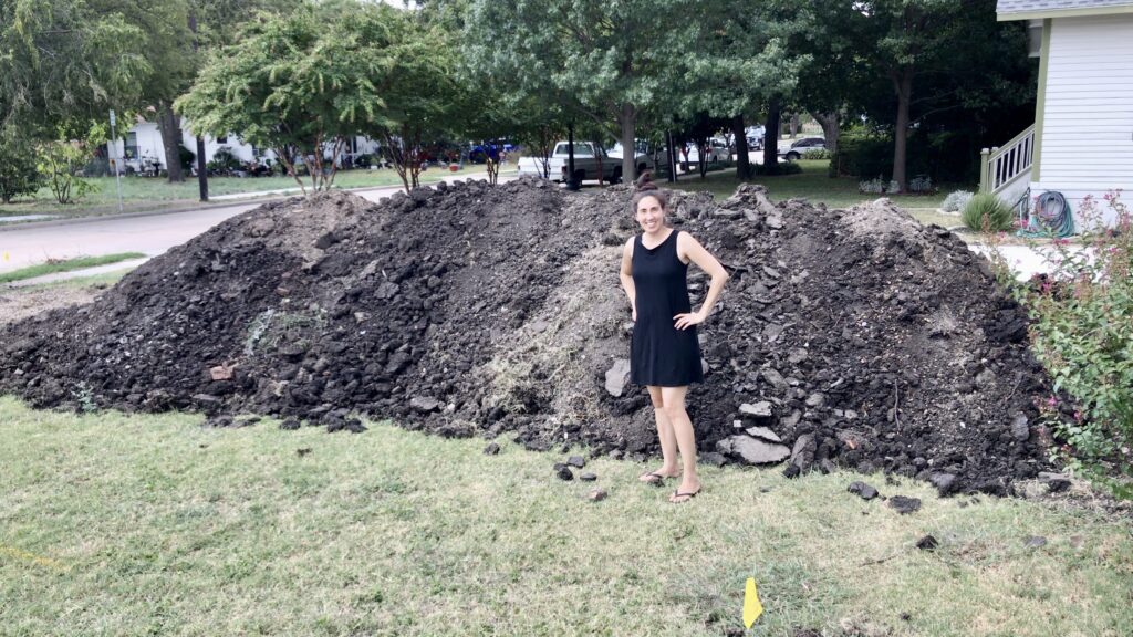 woman standing next to huge pile of dirt from landscape swale