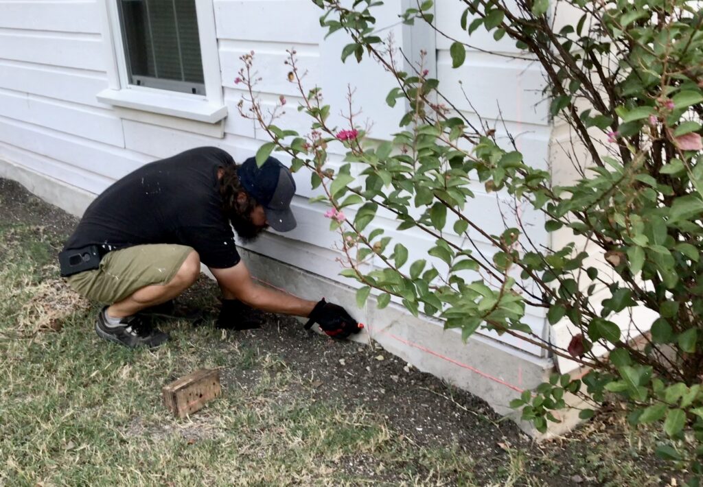 man marking red line on foundation of cottage
