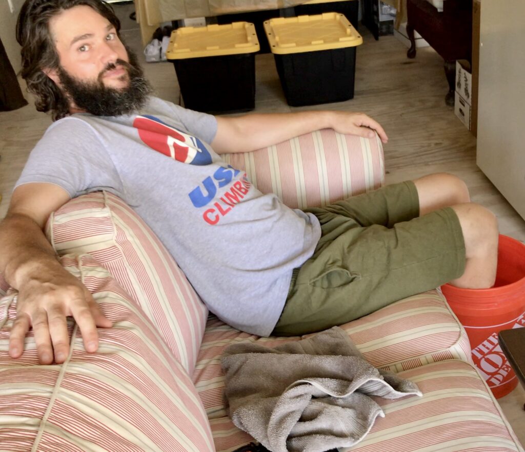 man sitting on couch with legs in bucket of water