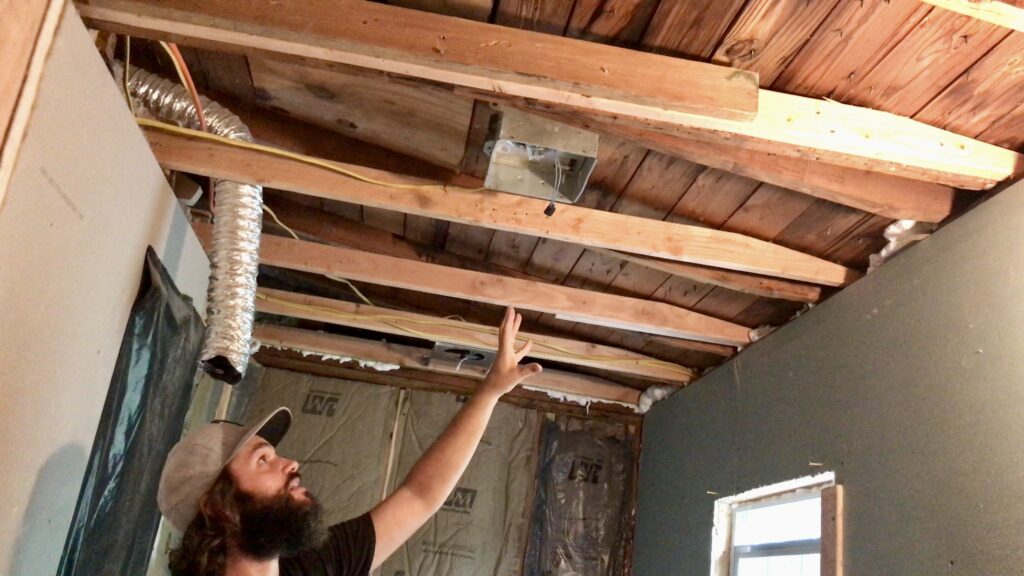 man pointing to bathroom ceiling framing exposed