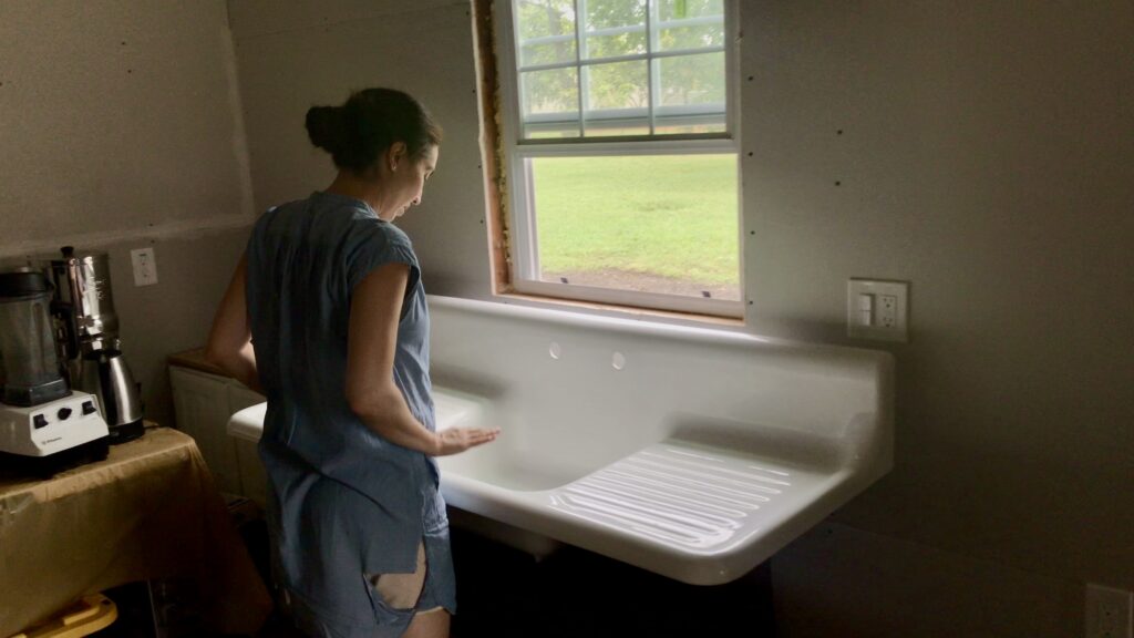 woman measuring height of antique cast iron sink