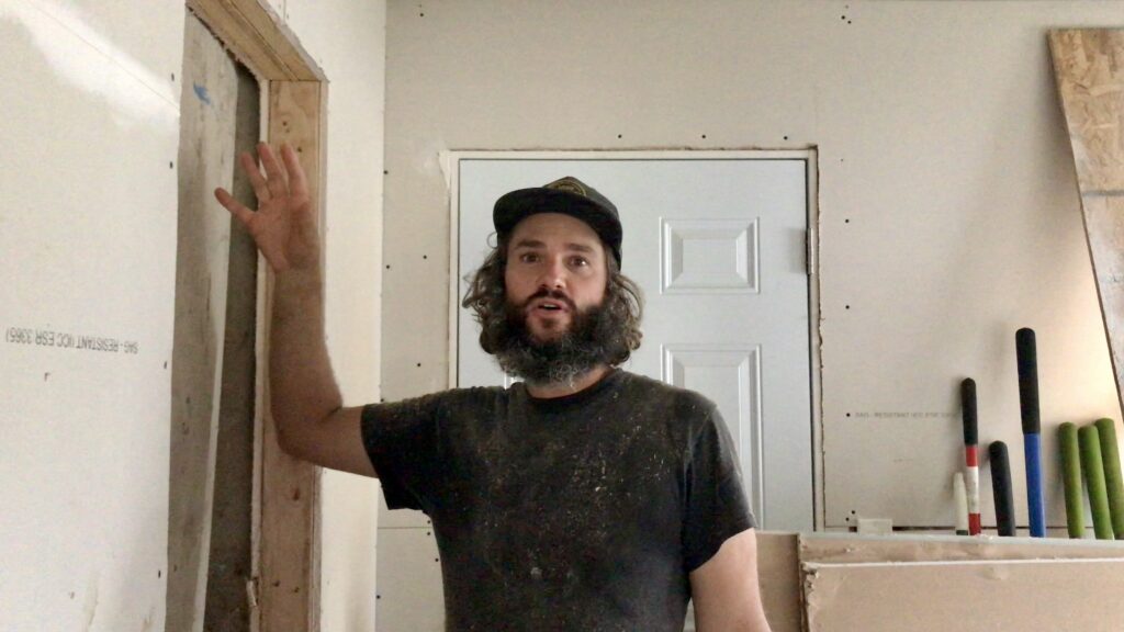 man standing in fixer upper with drywall around him
