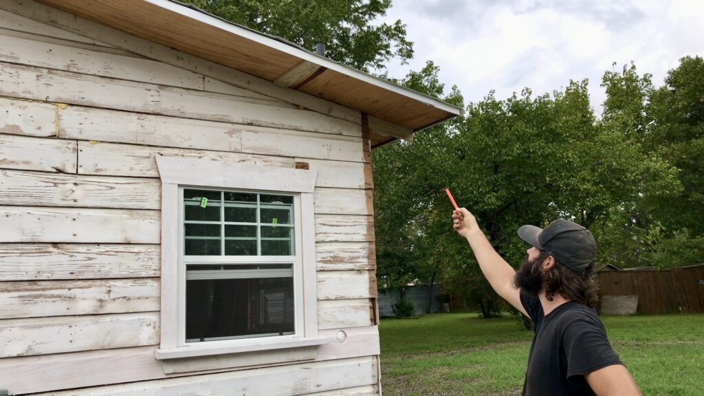 man pointing to old little cottage siding