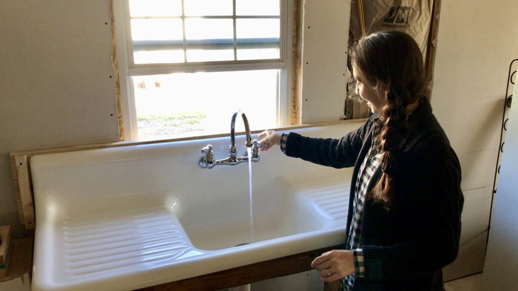 woman turning faucet on antique cast iron sink