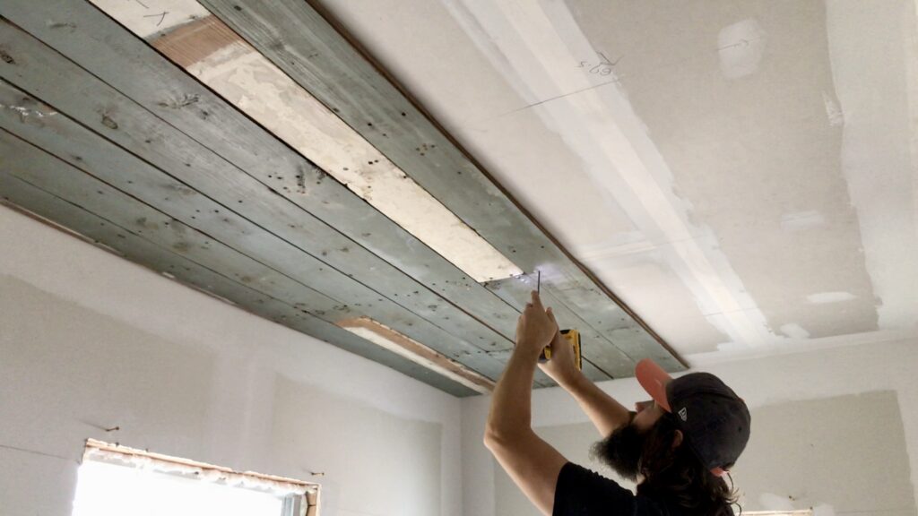 man installing salvaged wood ceiling