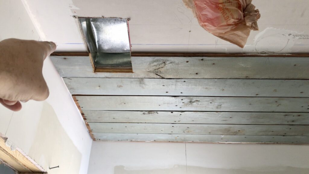 man pointing to HVAC duct cut out of drywall and old salvaged wood