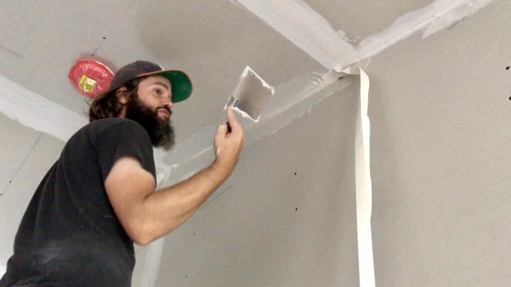 man mudding vaulted ceiling drywall