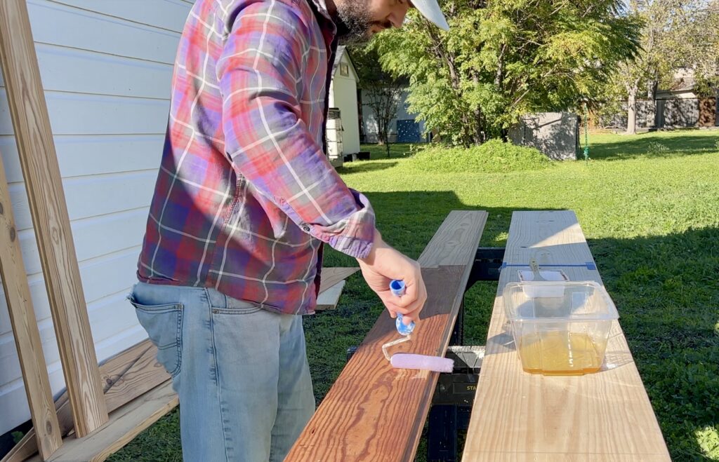 man applying tung oil on antique shiplap