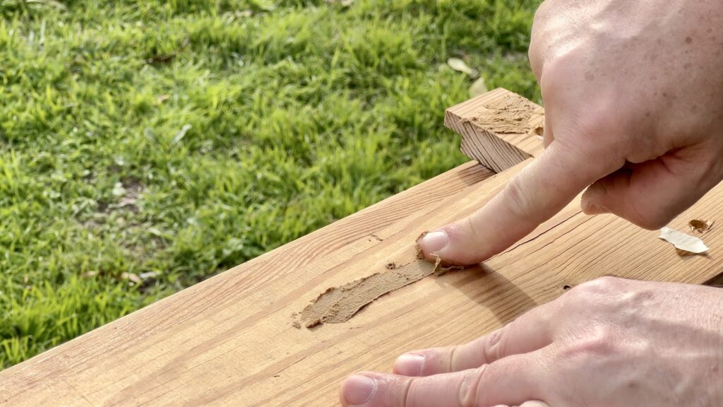 man applying wood filler on antique shiplap