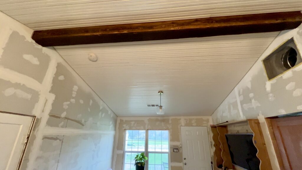 drywall prepped for antique shiplap with beadboard on the ceiling and pine beam at the peak
