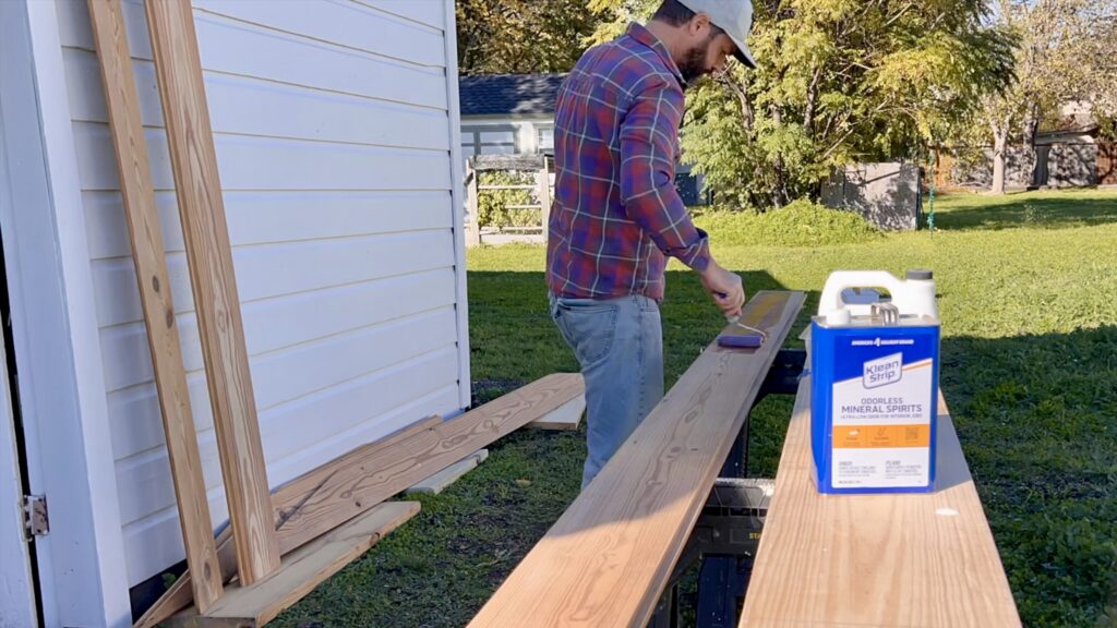 man applying tung oil on antique shiplap