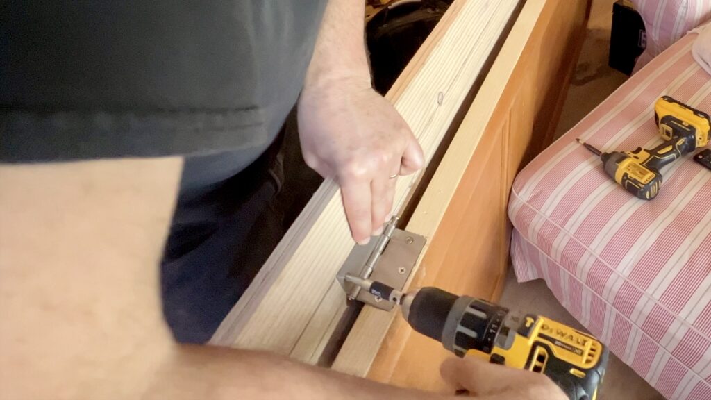man using cordless drill to screw hinges to custom door jamb