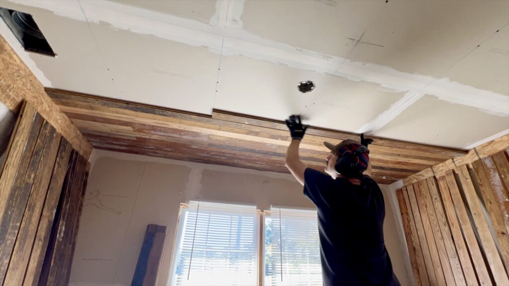 man installing reclaimed wood on ceiling