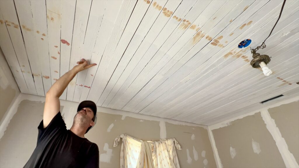 man applying wood filler on reclaimed wood ceiling
