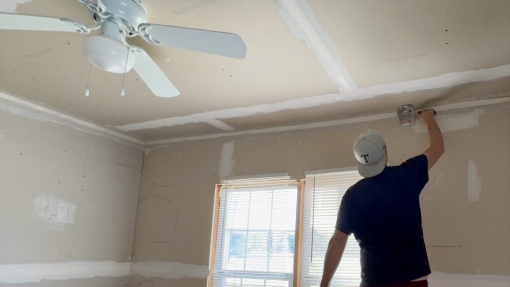 man drywall taping and mudding bedroom ceiling