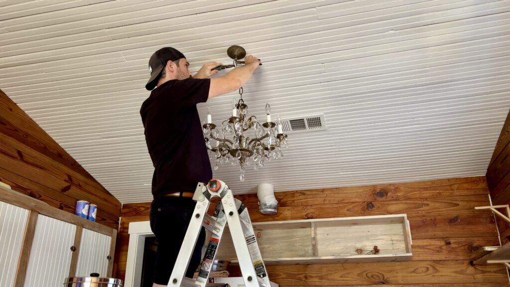 man installing antique chandelier in kitchen