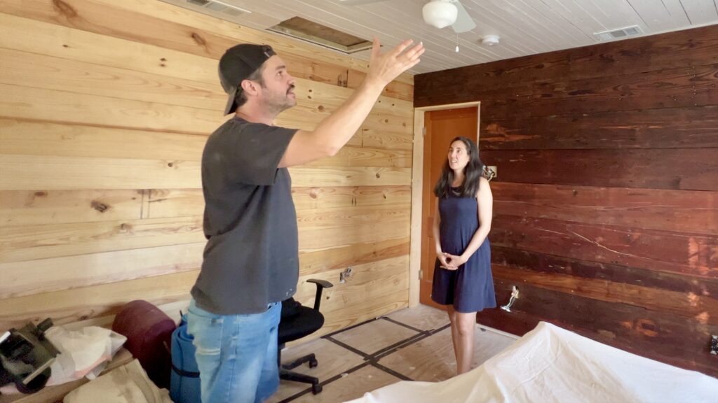 man motioning with hand to woman in room filled with reclaimed and new shiplap