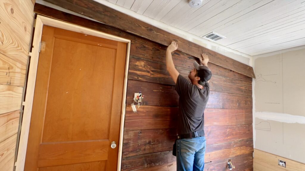 man installing old reclaimed shiplap on wall