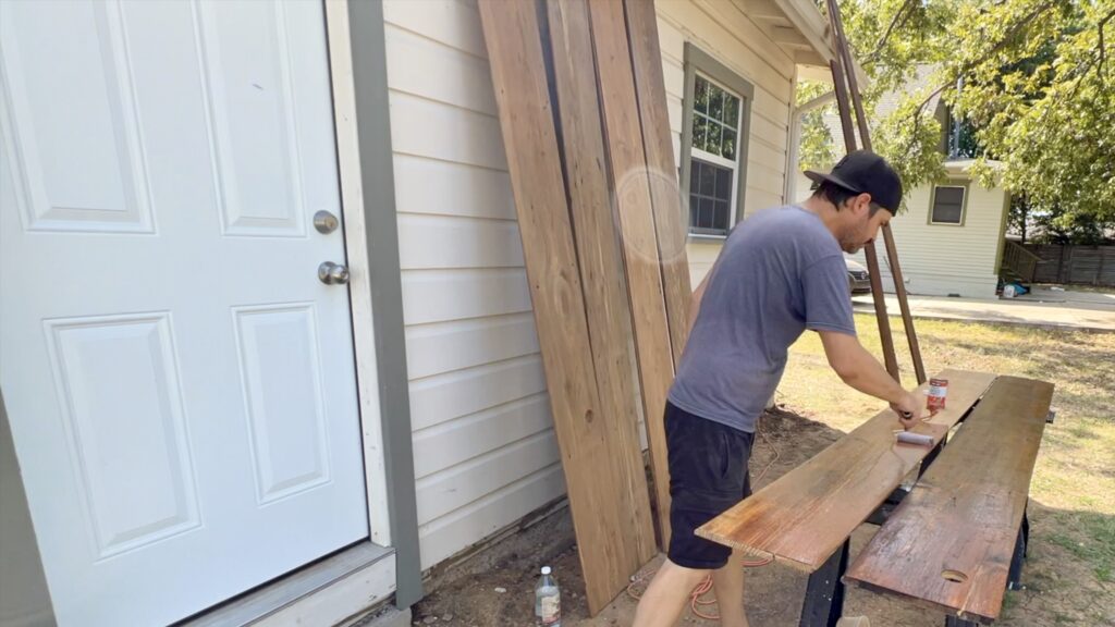 man applying tung oil to old reclaimed shiplap